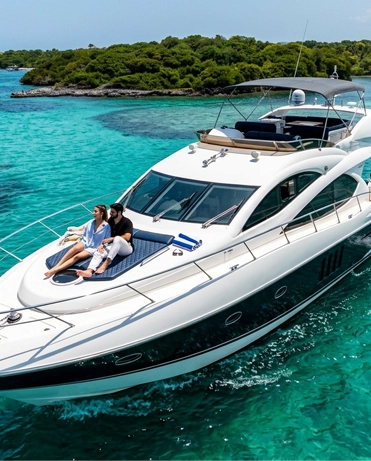 Couple relaxing on the bow of a private yacht anchored over turquoise water at the Rosario Islands near Cartagena.