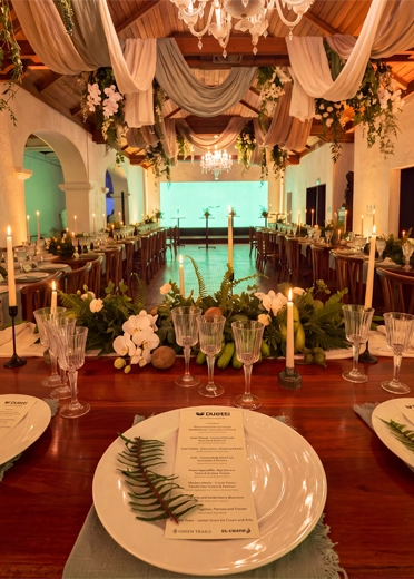 Corporate gala dinner setup in Colombia with long banquet tables, floral centerpieces and branded stage for an incentive event.