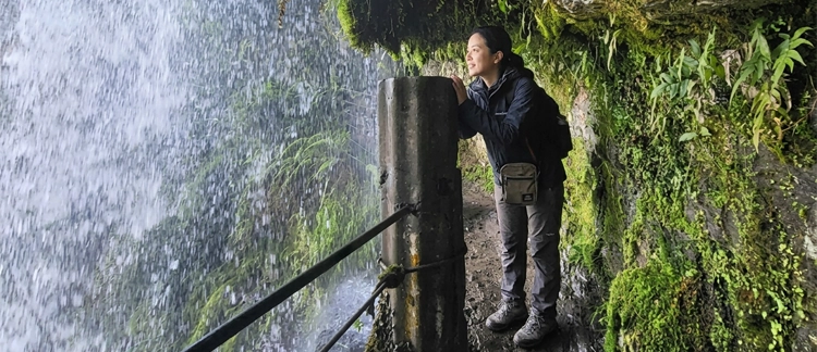 Hiker behind the misty curtain of the waterfall