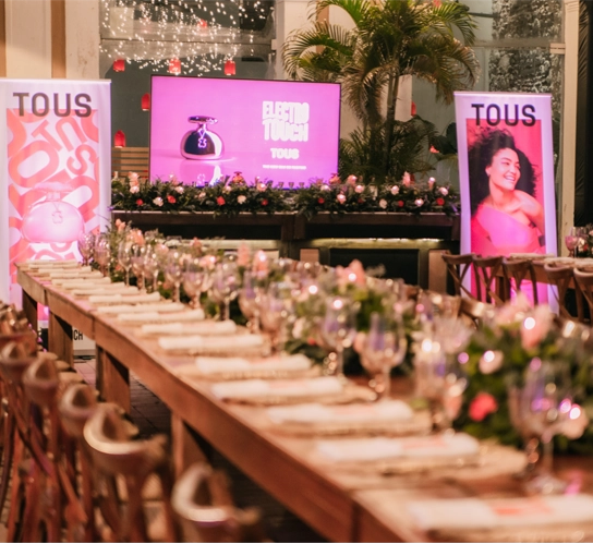 Corporate gala dinner setup in Colombia with long banquet tables, floral centerpieces and branded stage for an incentive event.