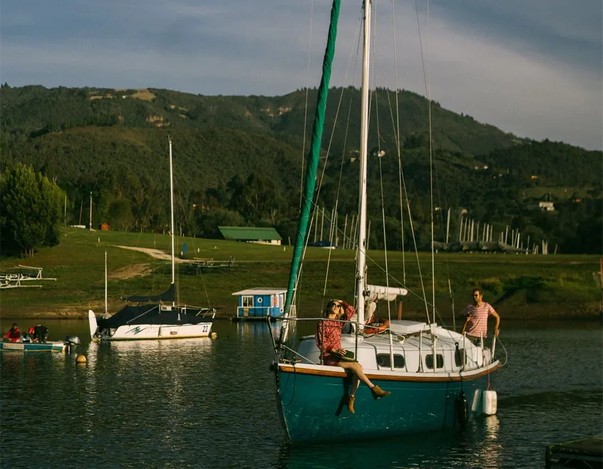Pareja navegando en velero en la Laguna de Guatavita con montañas andinas de fondo — tours privados desde Bogotá